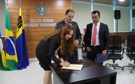 Sob o olhar do vice Daniel Pereira e do presidente do IDEP, João Faria, Maria assina do termo de psse