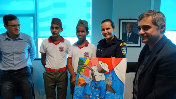 Acompanhados da diretora tenente Erica, os alunos José Soares e Wesley Fernandes entregaram quadro O Pescador ao secretário Caetano